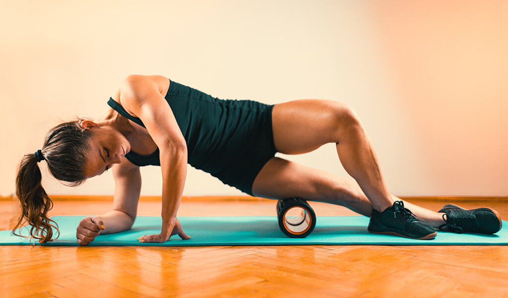 a woman using a muscle roller on her quadriceps
