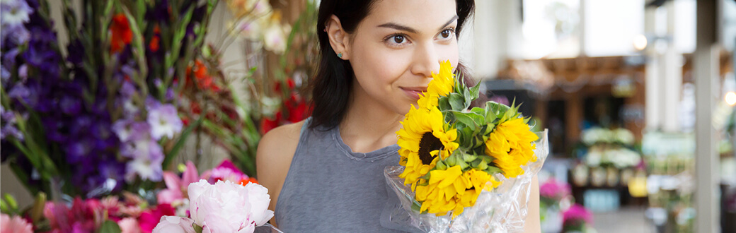A woman smelling a bouquet of sunflowers.